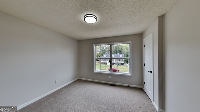 carpeted empty room with a textured ceiling