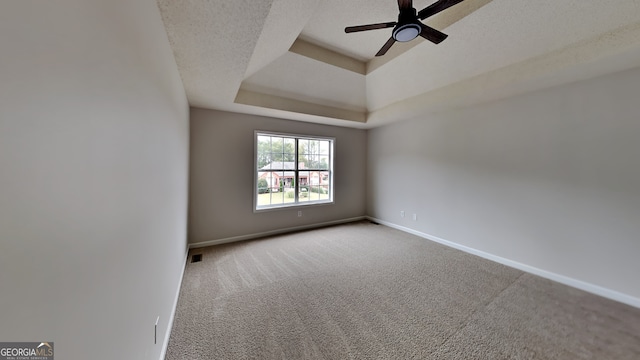 carpeted spare room with a tray ceiling, a textured ceiling, and ceiling fan