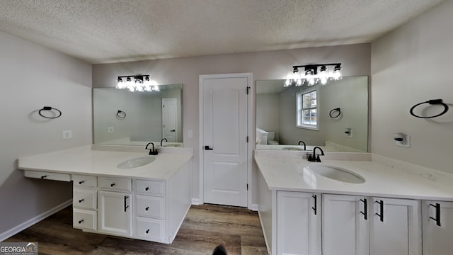 bathroom with hardwood / wood-style floors, vanity, a textured ceiling, and toilet