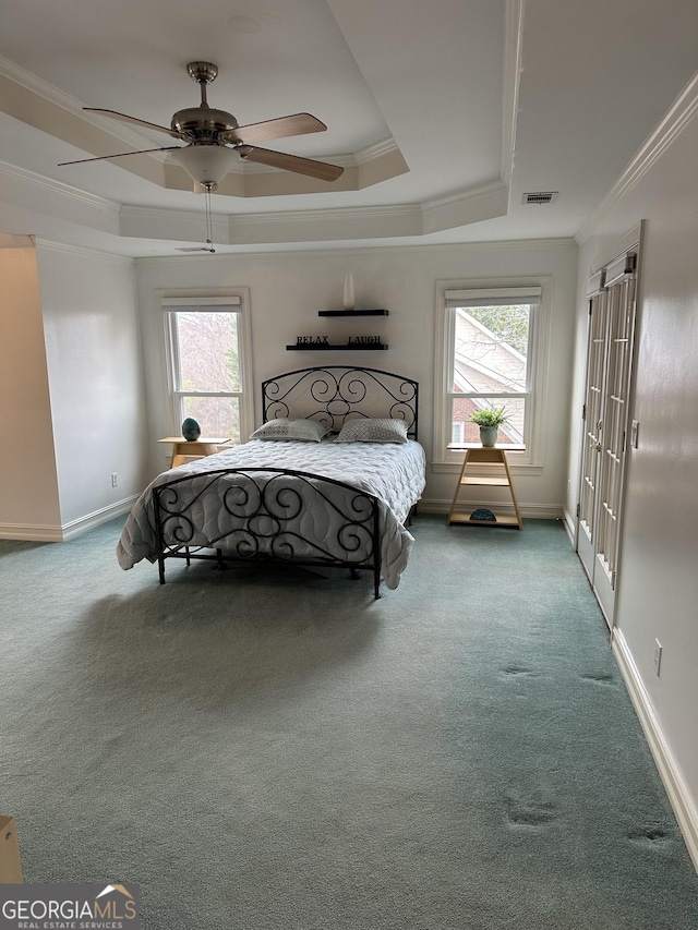 carpeted bedroom featuring ceiling fan, ornamental molding, and a raised ceiling