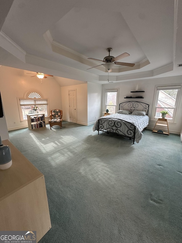 carpeted bedroom with crown molding, a tray ceiling, and multiple windows