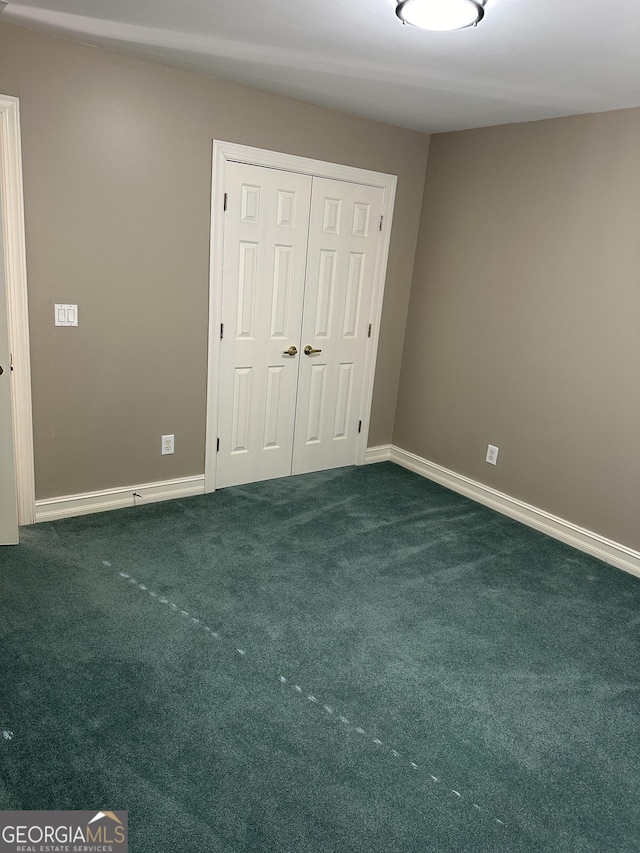 unfurnished bedroom with dark carpet and a closet