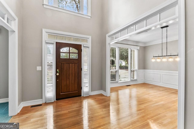 entrance foyer with crown molding, a towering ceiling, and wood-type flooring