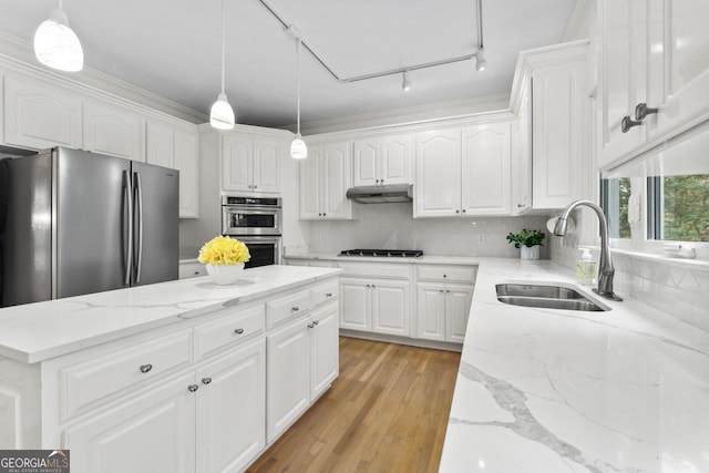 kitchen with decorative light fixtures, white cabinetry, sink, stainless steel appliances, and light stone countertops