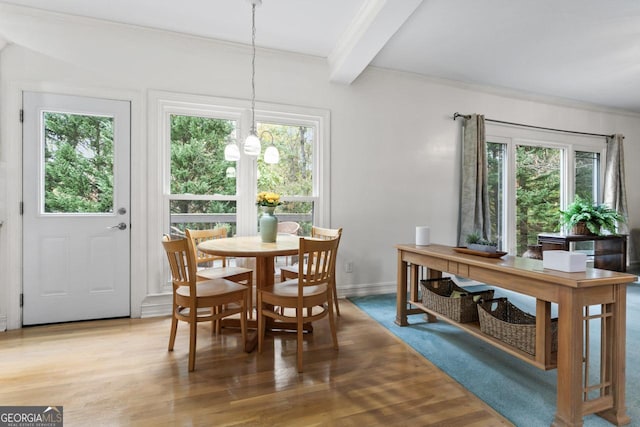 dining space with hardwood / wood-style flooring, ornamental molding, beam ceiling, and an inviting chandelier