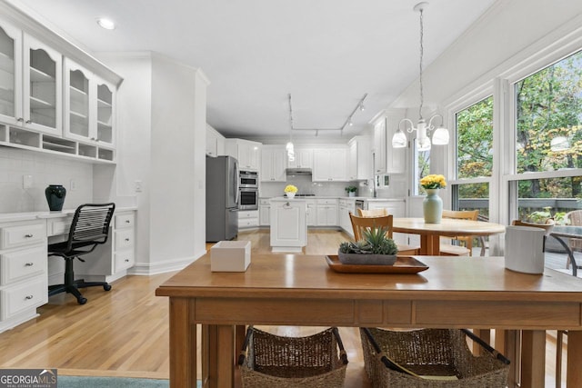 dining room with sink, a chandelier, light wood-type flooring, track lighting, and ornamental molding