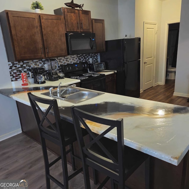 kitchen featuring dark wood-type flooring, kitchen peninsula, black appliances, sink, and tasteful backsplash