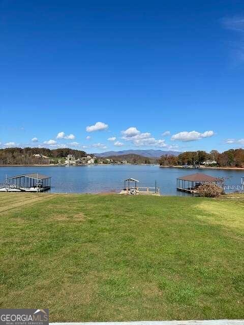 dock area with a water and mountain view and a lawn