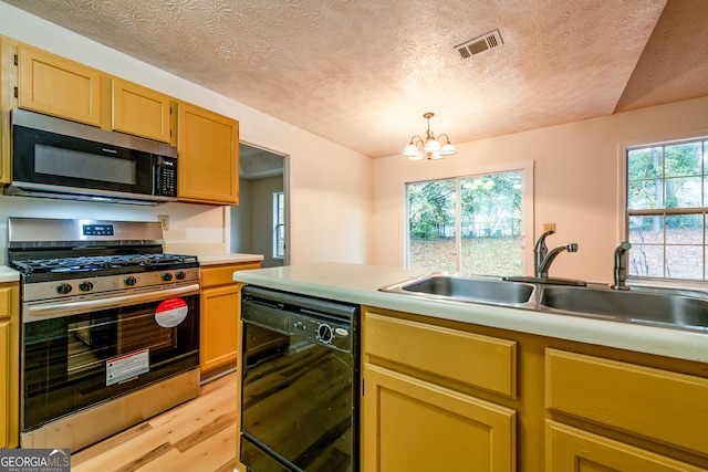 kitchen with sink, stainless steel appliances, an inviting chandelier, light hardwood / wood-style floors, and a textured ceiling