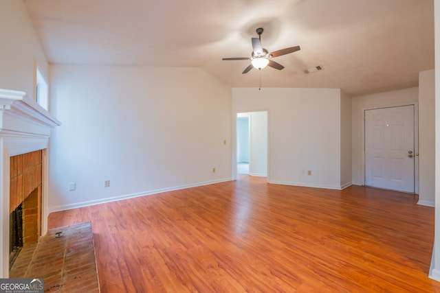 unfurnished living room with vaulted ceiling, a brick fireplace, ceiling fan, and light hardwood / wood-style floors