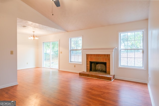 1121 Whisper Wind Dr, Mcdonough, GA 30253 - unfurnished living room featuring wood finished floors, ceiling fan, a tiled fireplace, vaulted ceiling, and a chandelier