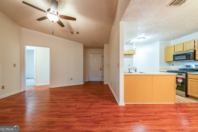 kitchen featuring kitchen peninsula, appliances with stainless steel finishes, a textured ceiling, ceiling fan, and light hardwood / wood-style floors