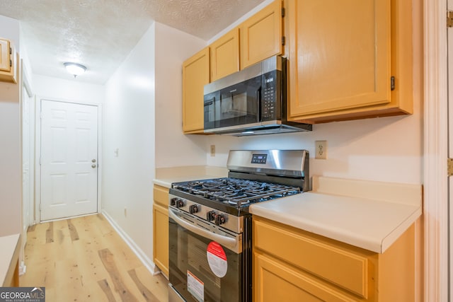 1121 Whisper Wind Dr, Mcdonough, GA 30253 - kitchen featuring appliances with stainless steel finishes, light wood-style floors, light brown cabinetry, light countertops, and a textured ceiling