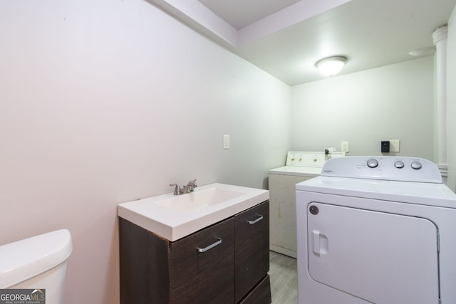 laundry room featuring washing machine and dryer, sink, and light hardwood / wood-style floors