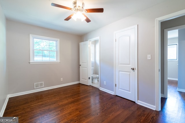 unfurnished bedroom with ensuite bathroom, dark wood-type flooring, and ceiling fan