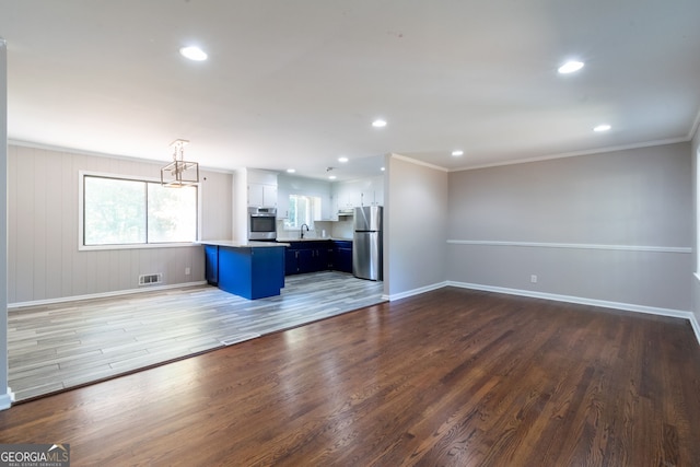 unfurnished living room featuring ornamental molding, dark wood-type flooring, and sink