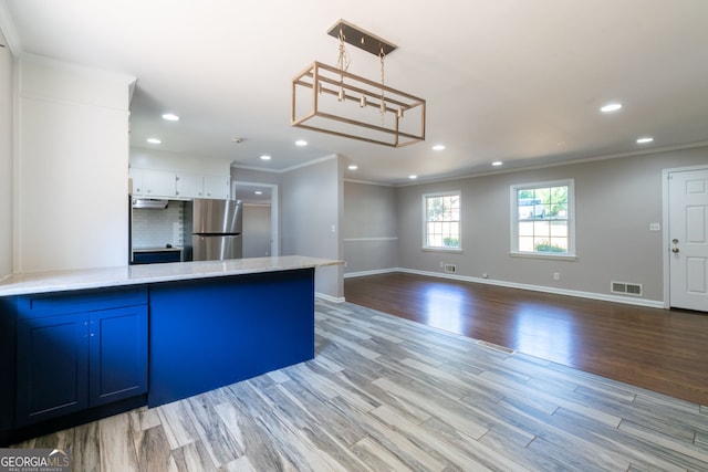 kitchen featuring pendant lighting, crown molding, stainless steel refrigerator, white cabinetry, and light wood-type flooring