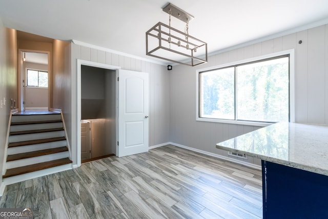 unfurnished dining area featuring crown molding, light hardwood / wood-style floors, and plenty of natural light