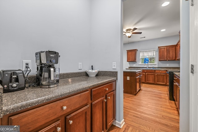 kitchen featuring black electric range oven, light hardwood / wood-style floors, ceiling fan, and sink