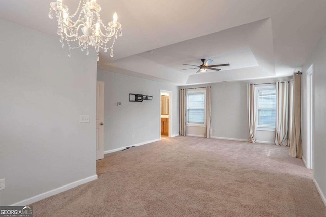 spare room with ceiling fan with notable chandelier, a raised ceiling, and carpet floors