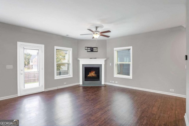 unfurnished living room featuring dark wood-type flooring and ceiling fan