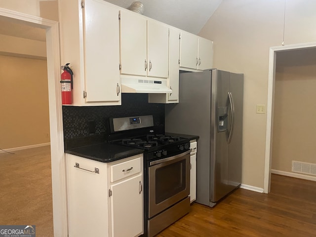 kitchen featuring appliances with stainless steel finishes, dark hardwood / wood-style floors, lofted ceiling, white cabinets, and decorative backsplash