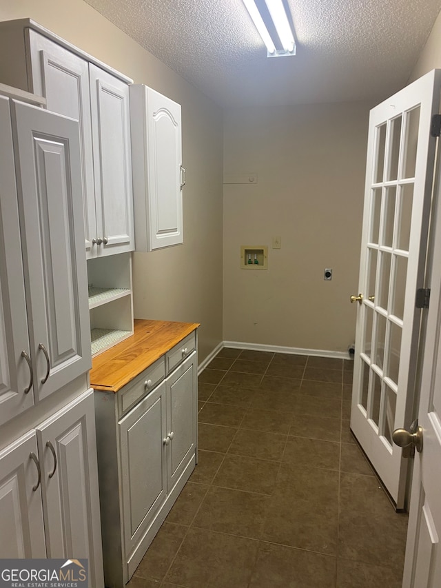 laundry area featuring dark tile patterned floors, hookup for a washing machine, cabinets, and a textured ceiling