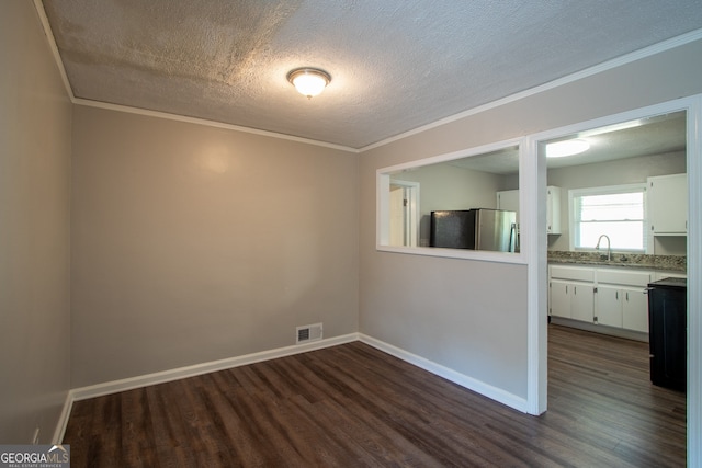 spare room with sink, a textured ceiling, dark hardwood / wood-style floors, and crown molding