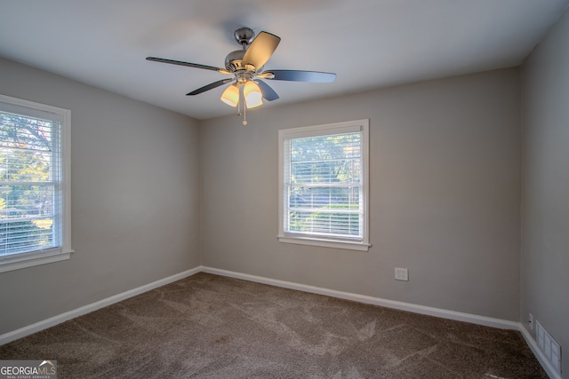 carpeted spare room featuring ceiling fan and plenty of natural light