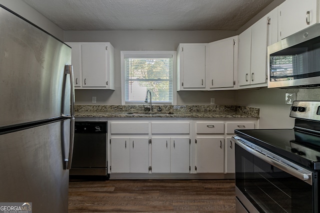 kitchen with appliances with stainless steel finishes, dark hardwood / wood-style floors, light stone countertops, sink, and white cabinets