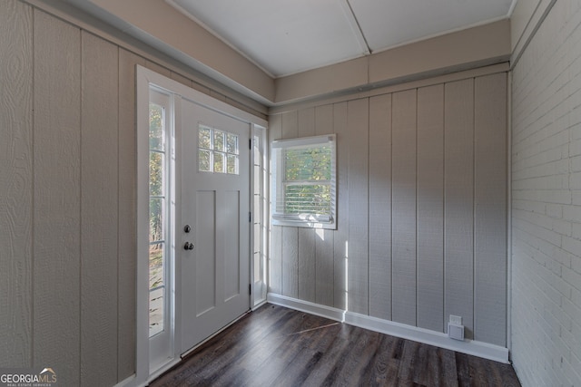 foyer featuring wood walls, brick wall, and dark hardwood / wood-style flooring