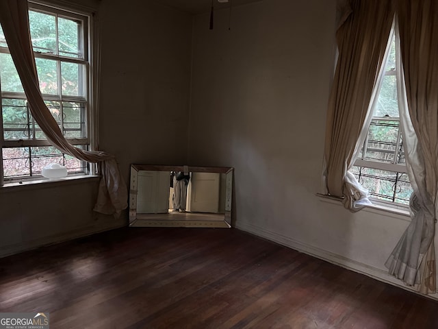 unfurnished room featuring a healthy amount of sunlight and dark wood-type flooring