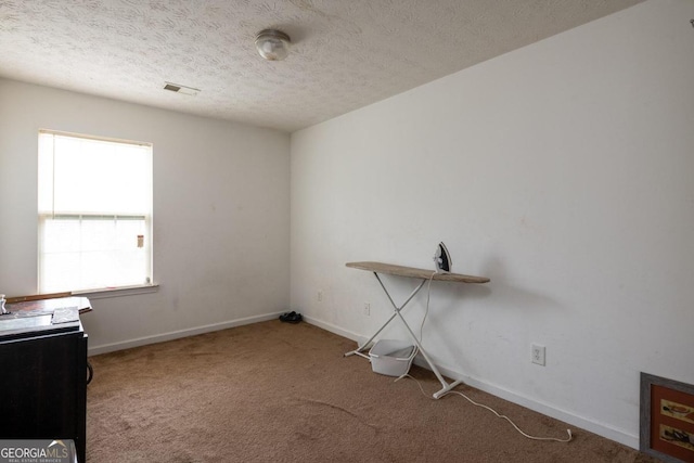 misc room featuring a textured ceiling and carpet