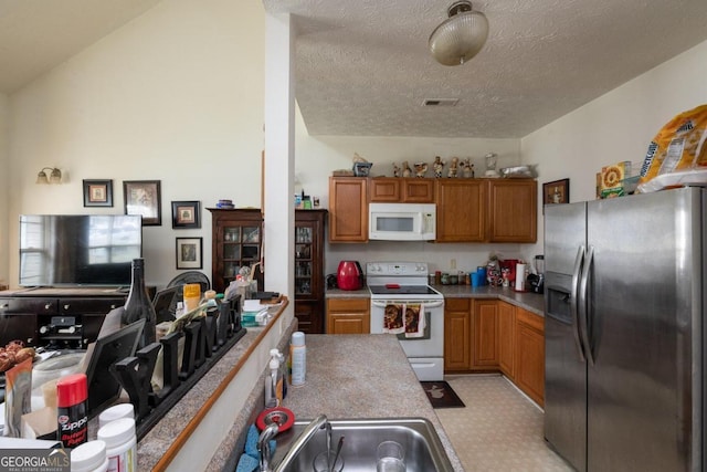 kitchen featuring white appliances, a textured ceiling, and lofted ceiling