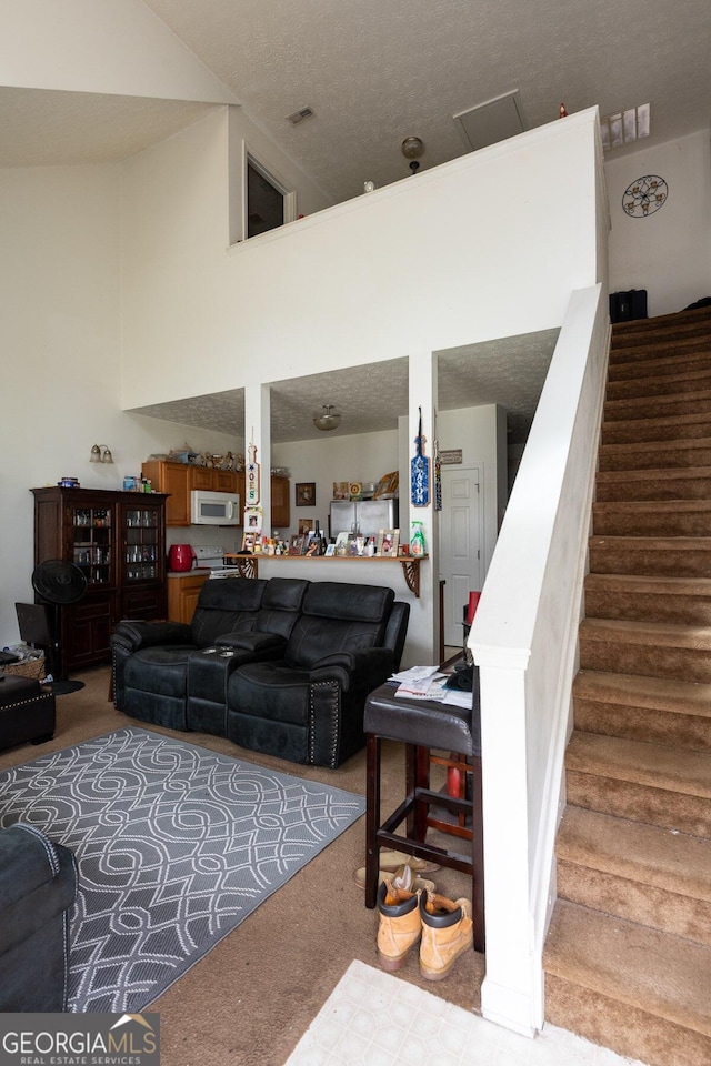 living room with a high ceiling and carpet flooring