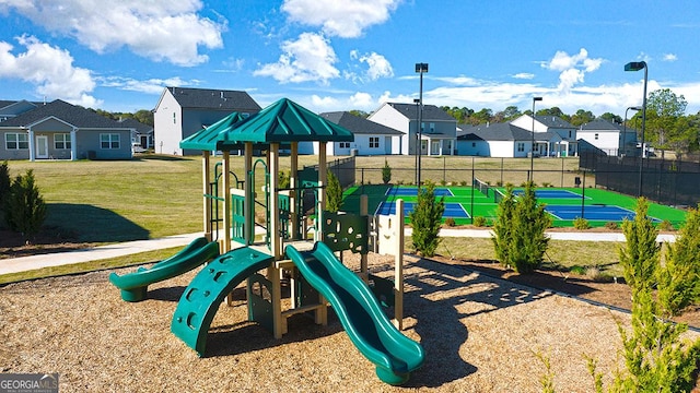 view of jungle gym with tennis court and a lawn