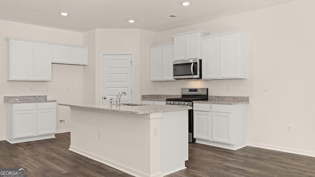 kitchen featuring dark wood-type flooring, sink, white cabinetry, stainless steel appliances, and a kitchen island with sink