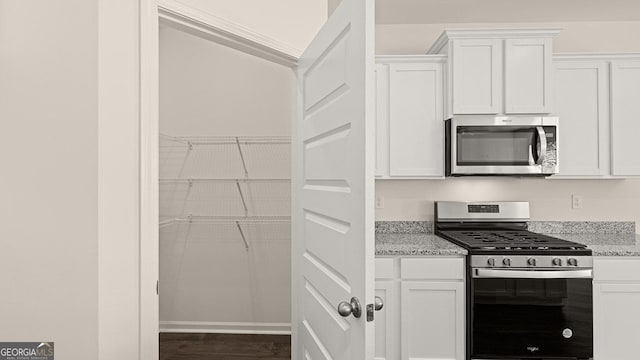 kitchen with light stone counters, stainless steel appliances, and white cabinets