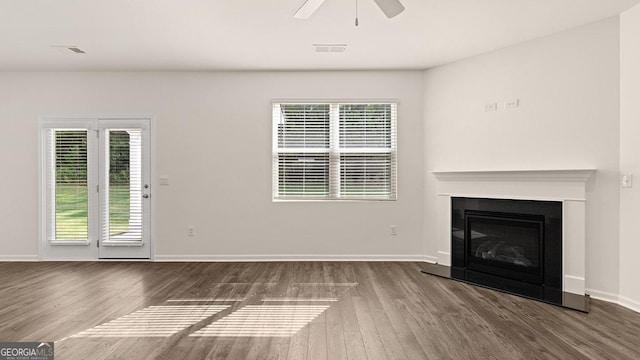 unfurnished living room with a healthy amount of sunlight, dark wood-type flooring, and ceiling fan