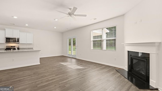 unfurnished living room featuring dark wood-type flooring, sink, and ceiling fan