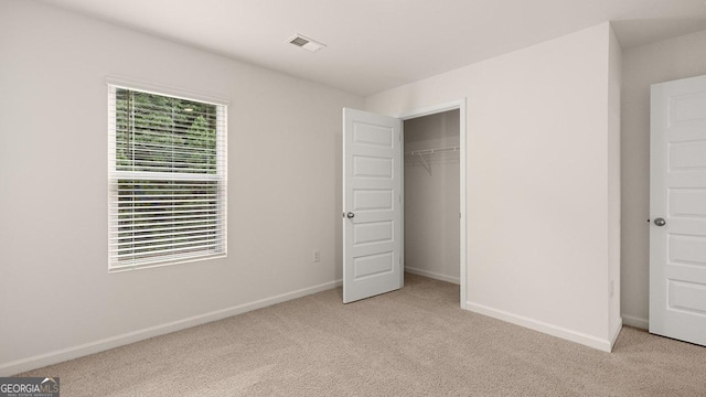 unfurnished bedroom featuring multiple windows, light colored carpet, and a closet