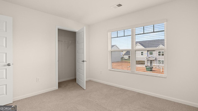 unfurnished bedroom with light colored carpet and a closet