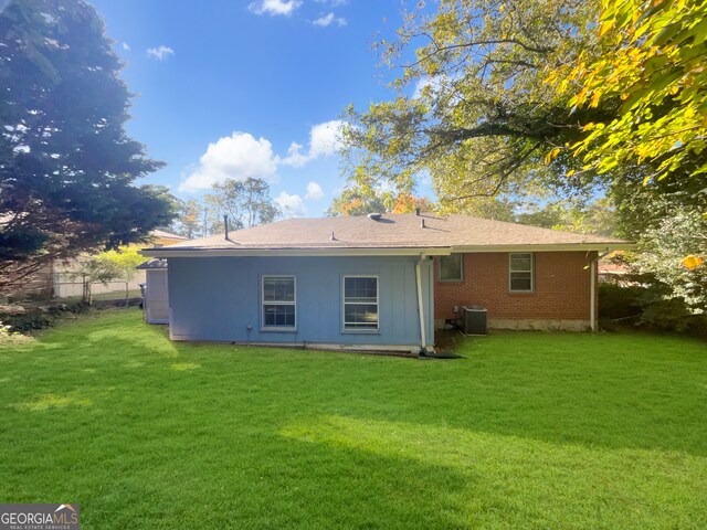 rear view of property with cooling unit and a yard