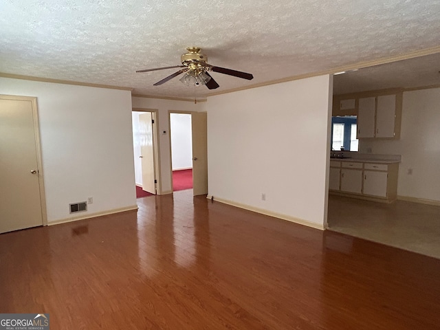 empty room featuring dark wood-type flooring, a textured ceiling, ceiling fan, and crown molding