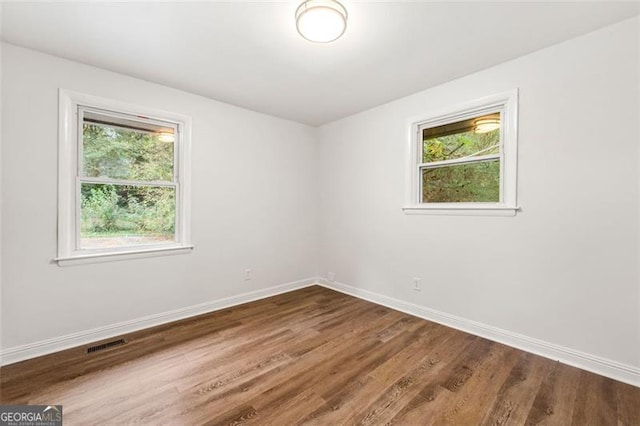 spare room featuring wood-type flooring and a healthy amount of sunlight