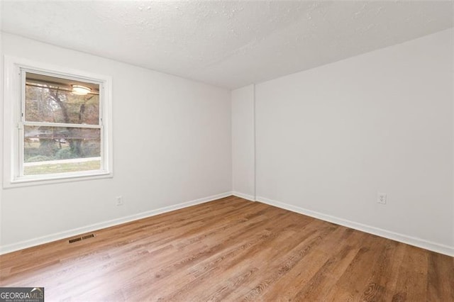 empty room with a textured ceiling and light wood-type flooring