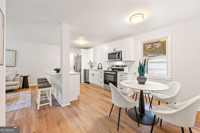 kitchen featuring appliances with stainless steel finishes, light hardwood / wood-style floors, white cabinetry, and sink