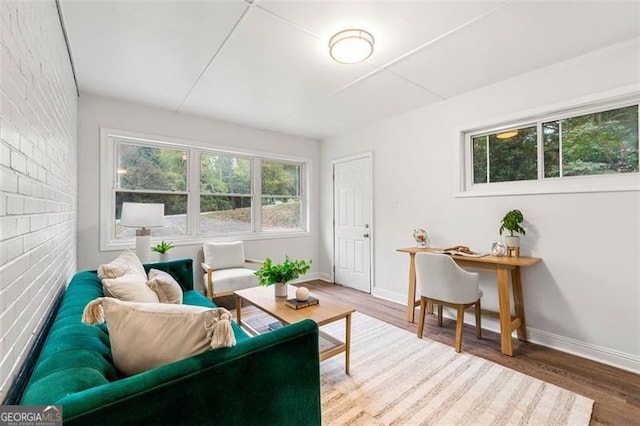 living room with hardwood / wood-style flooring and brick wall