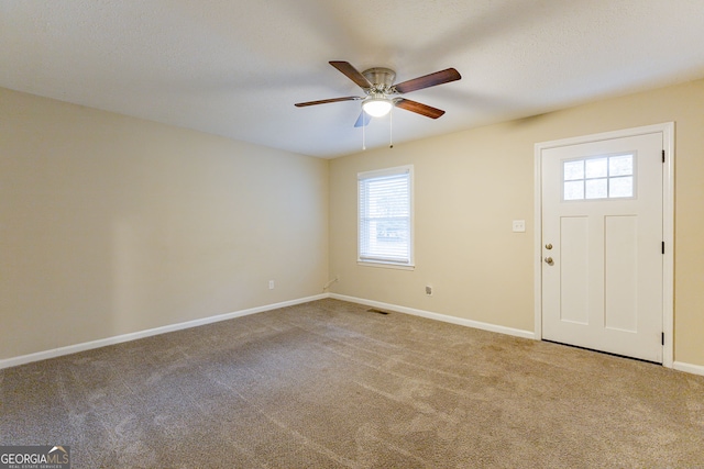 entrance foyer featuring ceiling fan, a healthy amount of sunlight, and carpet flooring