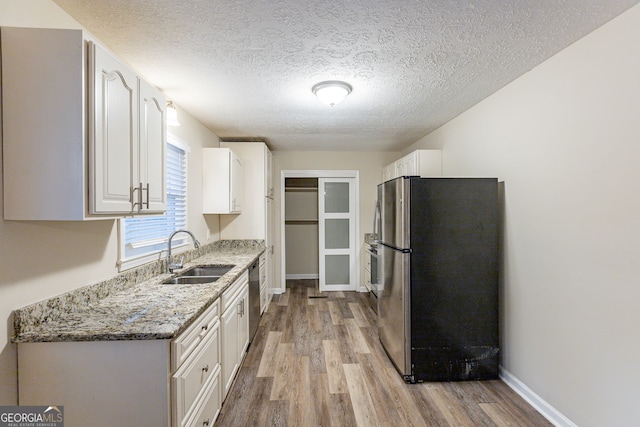 3730 Douglas Ridge Trl, Douglasville, GA 30135 - kitchen featuring appliances with stainless steel finishes, a sink, light wood finished floors, white cabinetry, and a textured ceiling